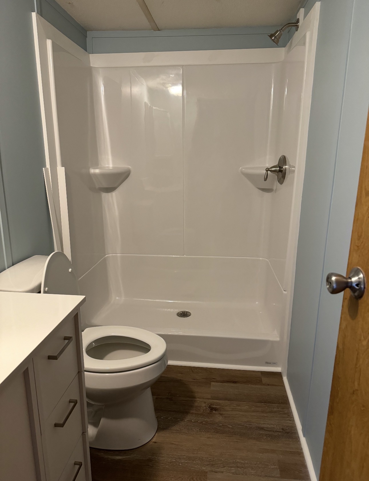 Completed bathroom with new tub-shower surround, toilet and vanity